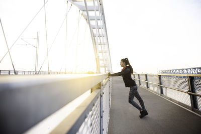 Side view of young woman on bridge against sky