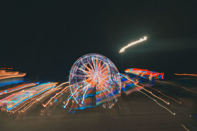 Illuminated ferris wheel against sky at night