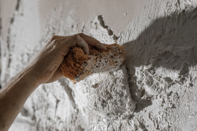 Close-up of hand holding stick against wall