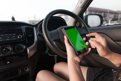 Midsection of woman using mobile phone while sitting in car