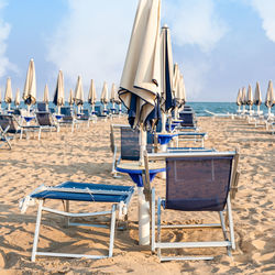 Deck chairs arranged on sand at beach
