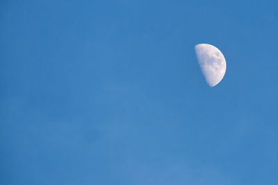 Low angle view of half moon against clear blue sky