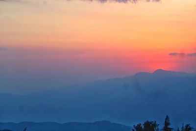 Scenic view of silhouette mountains against romantic sky at sunset