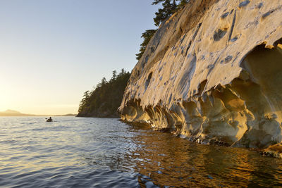 Rock formations in sea against clear sky