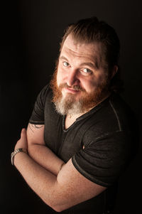 Portrait of man sitting against black background