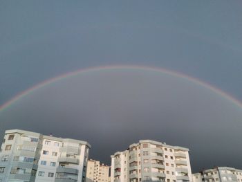 Low angle view of rainbow over buildings against sky