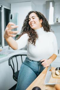 Portrait of young woman using mobile phone while sitting at home