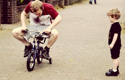 Full length of friends with bicycle on street in city