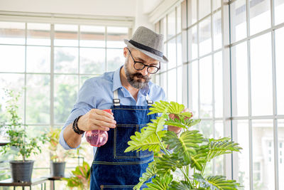 Botanist watering pant at greenhouse