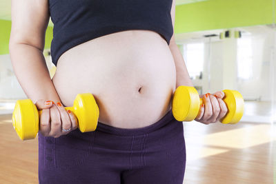 Midsection of pregnant woman exercising in gym