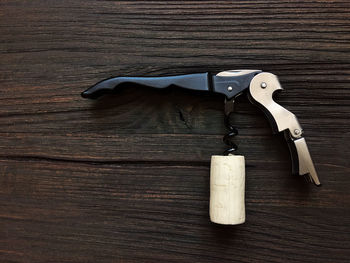 Close-up of corkscrew and cork on wooden table