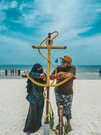 Man and woman standing at beach against sky