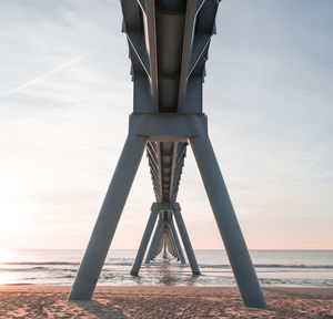 Bridge at beach over sea against sky