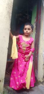 Full length of woman standing against pink wall