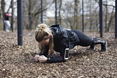 Full length of female athlete performing plank position in forest