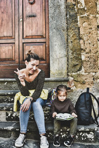 Portrait of smiling mother with daughter sitting on steps