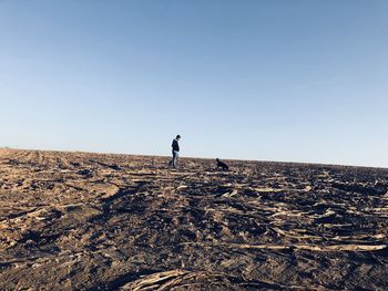 Man walking on land against clear sky