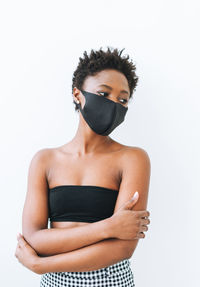 Beautiful young african american woman in black top and face mask isolated on white background