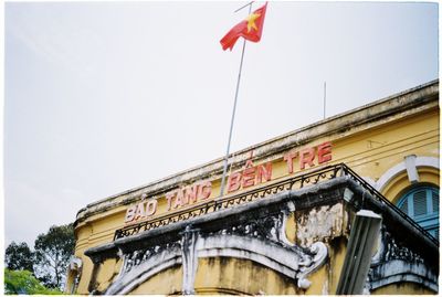 Low angle view of flags on building against sky