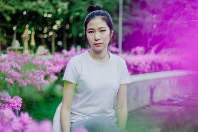 Portrait of teenage girl standing on pink flowering plants