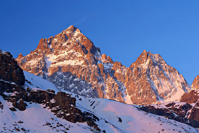 Scenic view of snowcapped mountains against clear blue sky