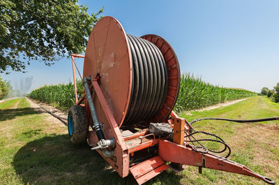 Rusty wheel in field against clear sky