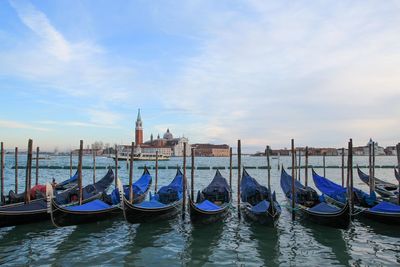 Boats moored in water against sky