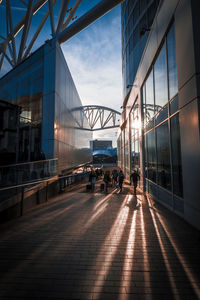 People on bridge in city against sky at sunset