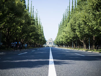 Road amidst trees in city against clear sky