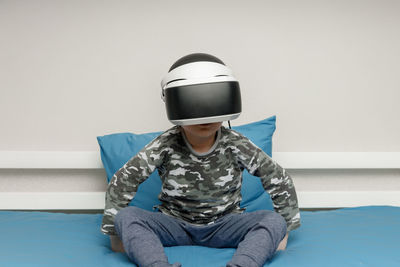 Midsection of boy sitting against wall at home