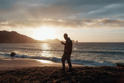 Full length of man standing on beach during sunset