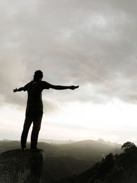 Rear view of woman standing on mountain against sky