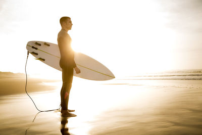 Rear view of man with surfboard on beach