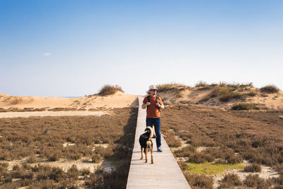 Rear view of man with dog against sky