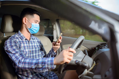 Full length of man using mobile phone in car