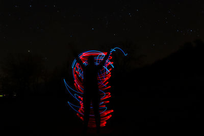 Silhouette person standing against light painting at night