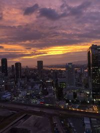 Illuminated buildings in city against sky during sunset