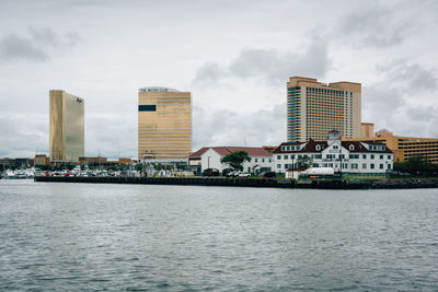 Sea by buildings against sky in city