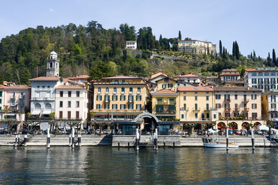 Buildings by river against sky in city