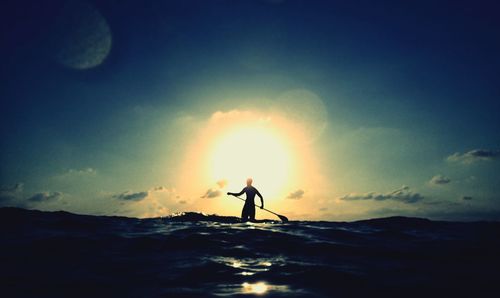 Silhouette man standing on shore against sky during sunset