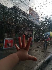 Person seen through wet glass window in rainy season