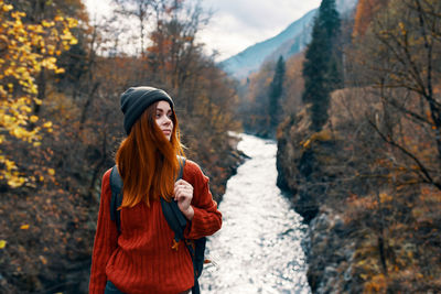 Smiling young woman standing by tree during autumn