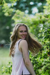 Portrait of smiling young woman against tree