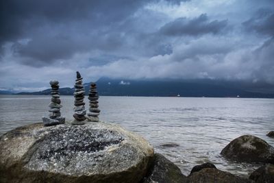 Stack of rocks by sea against sky