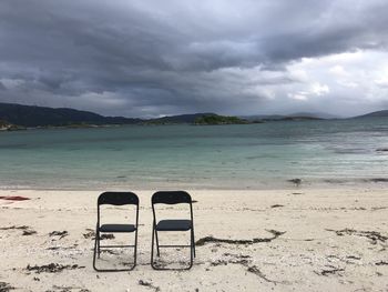 Chair on beach against sky