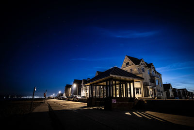 Houses by street against sky at night