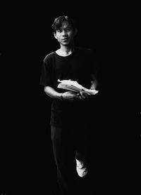 Full length of young man standing against black background