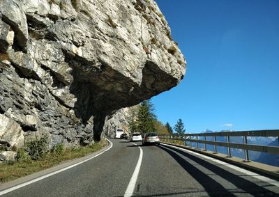 Road passing through rock formation against sky