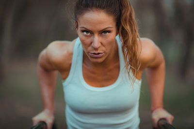 Portrait of woman exercising on bars in park