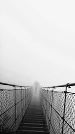Footbridge against sky during foggy weather